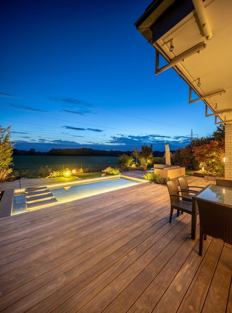 eine schöne dunkle Holzterrasse mit Pool in der Abenddämmerung